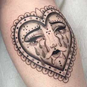 Black and grey tattoo of a heart with a crying face inside