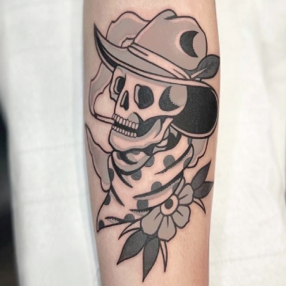 Black and grey tattoo of a scull wearing a cowboy hat and polka-dot scarf smoking a cigarette