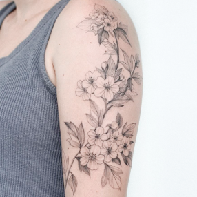 Floral black ink fine line tattoo going along the upper arm