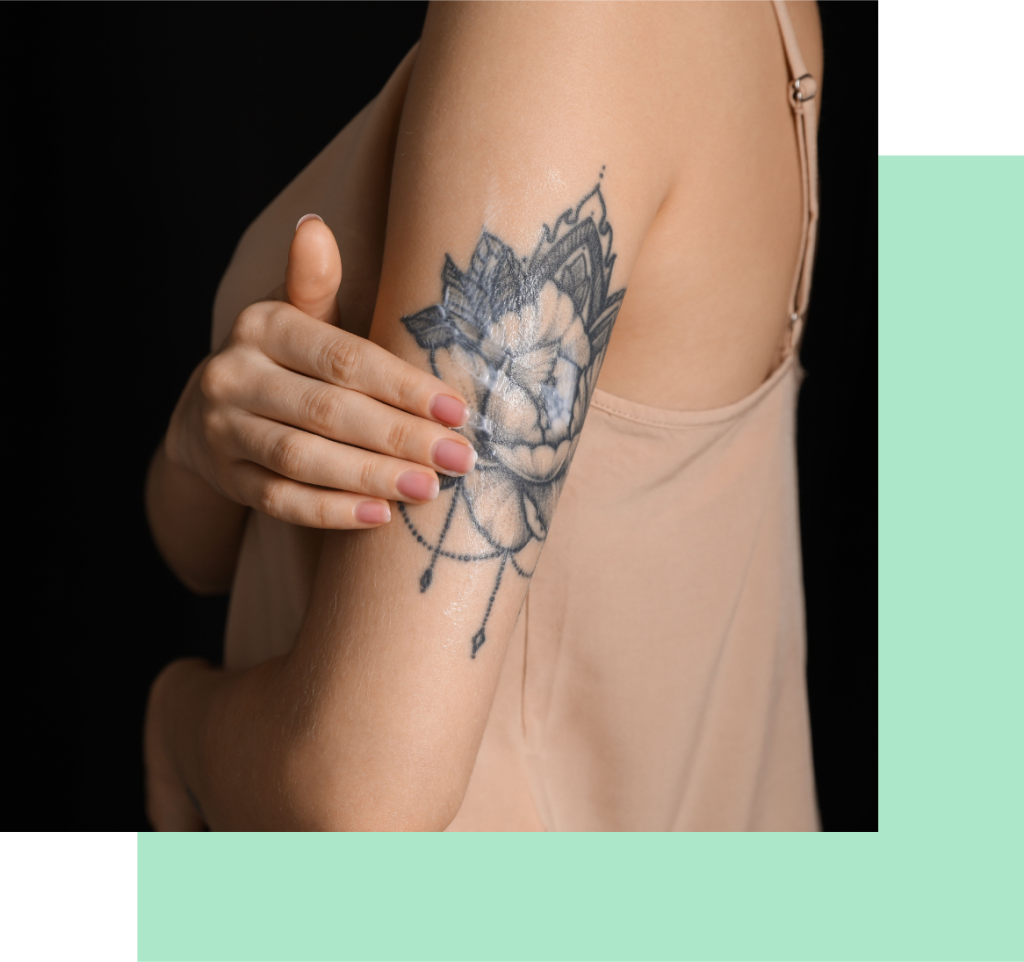 woman putting cream on an upper arm tattoo